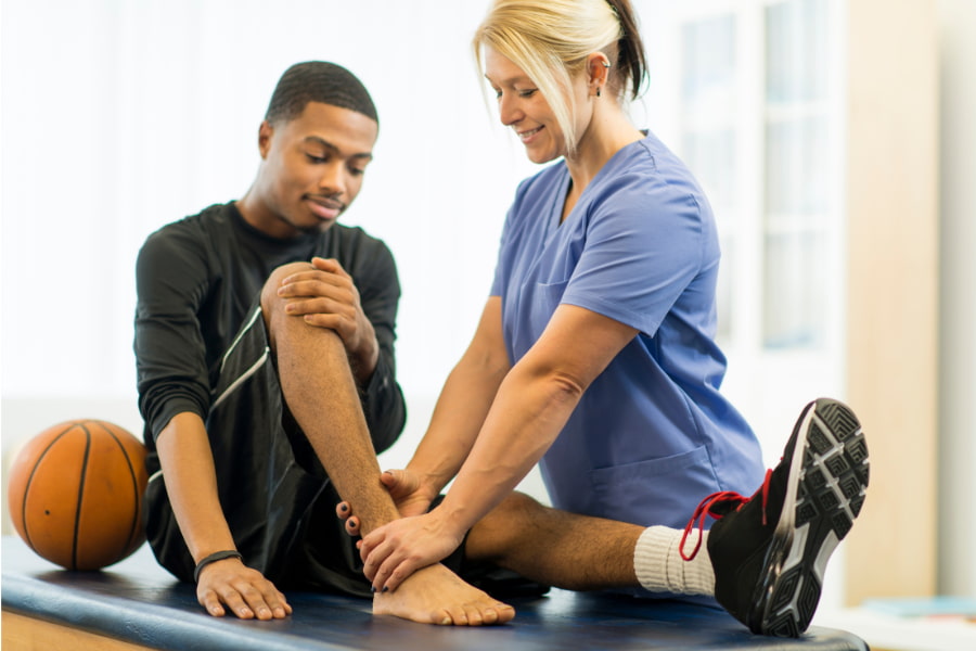 man having his ankle examined by a physical therapist